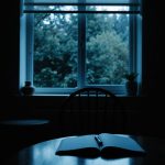 Open notebook on table near dimly lit window.