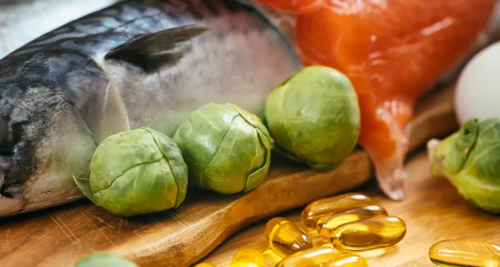 Fish, Brussels sprouts, omega-3 capsules on cutting board.